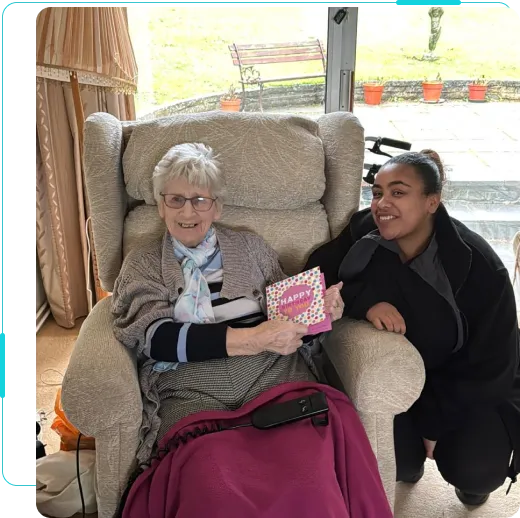 A photo of one of SilverBirch Healthcare customers on their birthday with their live in carer. The client is holding a birthday card