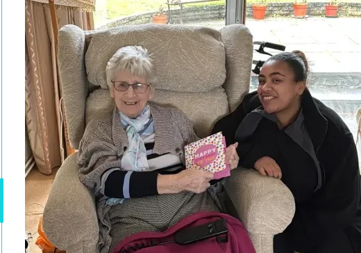 A photo of one of SilverBirch Healthcare customers on their birthday with their live in carer. The client is holding a birthday card